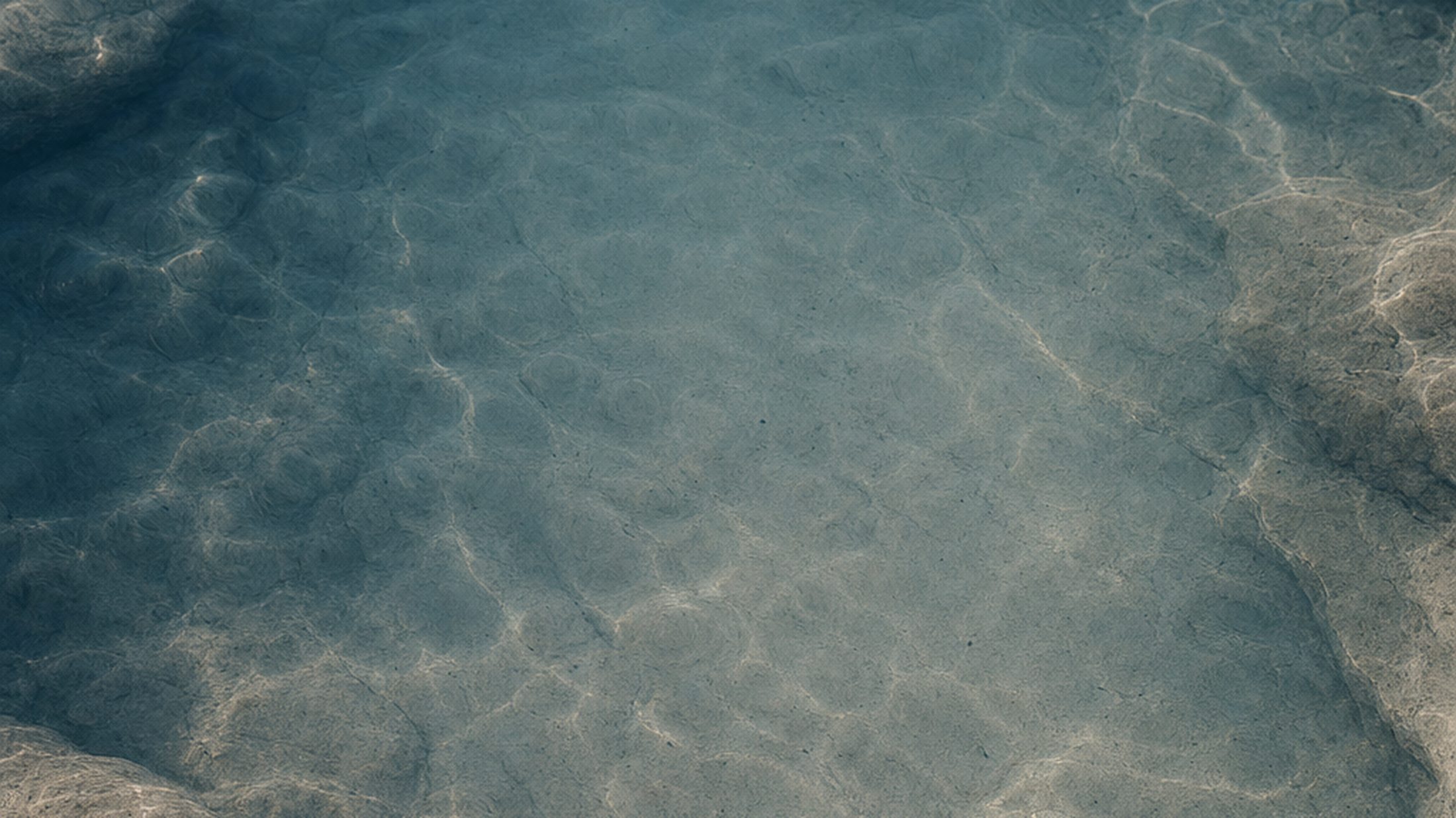 Still water over pale sandstone